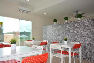 a dining room with white tables and red chairs at The Baiti in Bandar  Pusat Jengka