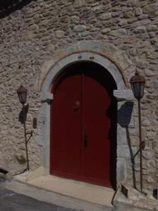 une porte rouge sur un bâtiment en pierre avec deux lumières dans l'établissement Pyrgos Of Mystra, à Mystras