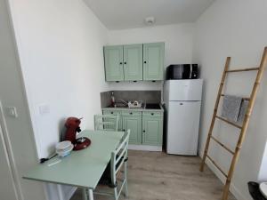a kitchen with green cabinets and a table and a refrigerator at Appart 1er étage Angers Chalouère in Angers
