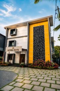 a building with a yellow door and flowers in front at Levora Suits in Kottayam