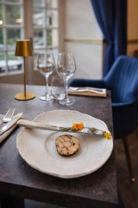 a plate with a cookie on a table with wine glasses at Château De La Caze Piscine & Spa - Ste Enimie in Sainte-Énimie