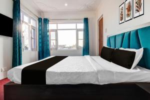 a bedroom with a large bed with blue curtains at Hotel O Wave Inn in Srinagar