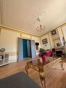 a living room with a table and a chandelier at Hotel du chateau blanc in Saint-Aubin-lès-Elbeuf