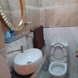 a bathroom with a sink and a toilet and a mirror at Guest House MM in Saly Portudal