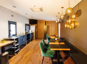a restaurant with tables and green chairs in a room at &Tales Suites - Óbidos in Óbidos