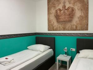 two beds in a room with a crown on the wall at Mariazellerhof Room 015 in Sankt Pölten