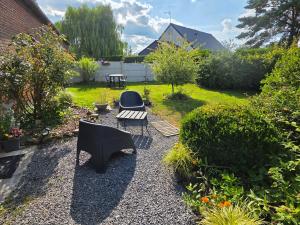 a garden with two black chairs and a table at Studio Bienvenue du côté de chez nous avec jardin privatif in Wignehies