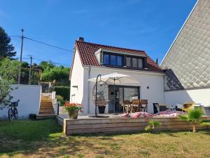 a white house with an umbrella and a patio at La parenthèse de la Bouvaque in Abbeville +23 photos