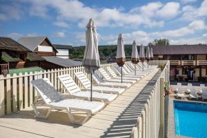 a row of lounge chairs with umbrellas next to a pool at Золотий Павлін in Solotvyno
