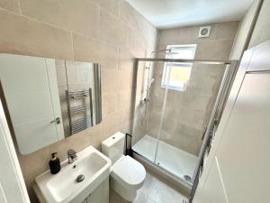 a bathroom with a shower and a toilet and a sink at Stylish 2BR Flat 3 Mins to Wembley Stadium in London