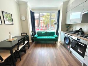 a living room with a green couch and a table at Stylish 2BR Flat 3 Mins to Wembley Stadium in London