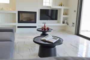 a living room with a table with a book and a tv at VILLA GALINI NAFPLIO with Panoramic View I in Nafplio