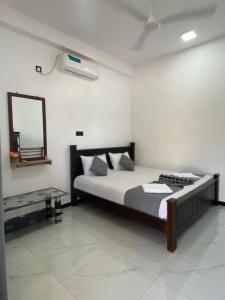 a bedroom with a bed and a mirror on the wall at NRT Beach Hotel in Trincomalee