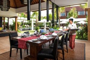 a woman standing at a table with a tray of food at Villa Anam in Seminyak