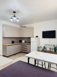 a kitchen with a table and a white refrigerator at Raduga West Balor in Koshkolʼ