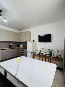 a room with a white table and a kitchen at Raduga West Balor in Koshkolʼ