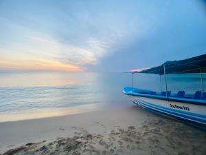 a boat sitting on the beach at sunset at NRT Beach Hotel in Trincomalee