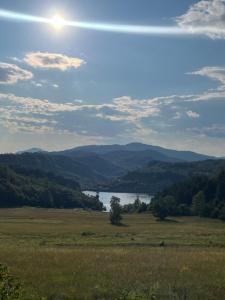 a view of a field with a lake and mountains at HERC domaćinstvo in Nova Varoš +5 photos
