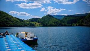 a dock with chairs and a boat on a lake at HERC domaćinstvo in Nova Varoš
