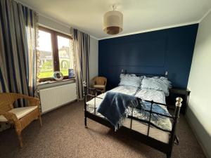 a blue bedroom with a bed and a window at Domek nad jeziorem in Kikół