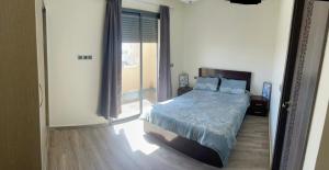 a bedroom with a bed and a sliding glass door at Appart 5min plage, plein centre in Sidi Rahal