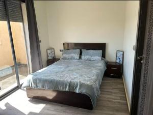 a bedroom with a large bed and a large window at Appart 5min plage, plein centre in Sidi Rahal