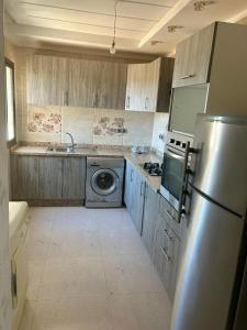 a kitchen with a refrigerator and a washing machine at Appart 5min plage, plein centre in Sidi Rahal