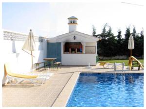 a swimming pool with chairs and a building with a house at Resort Solar Veiguinha in Carvoeiro