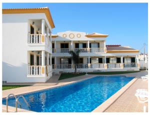 a villa with a swimming pool in front of a house at Resort Solar Veiguinha in Carvoeiro