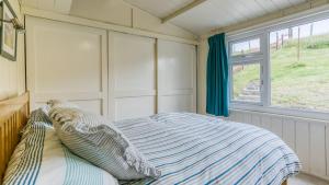 a bedroom with a bed and a window at Beach Bungalow in Nefyn