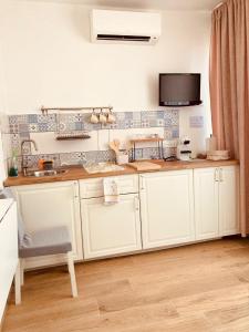 a kitchen with white cabinets and a tv on the wall at Casa Di Luce Junior Con Parcheggio Privato in Montesilvano