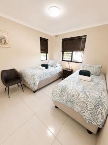 a bedroom with two beds and a chair in it at Unit 5 in Serengeti Complex, Bloemhof, Bellville in Blomtuin