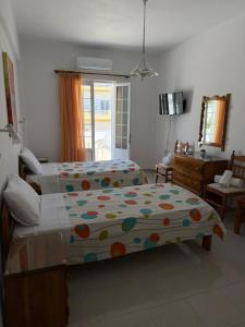 a bedroom with two beds and a desk and a mirror at Smalis Studios in Lakkíon