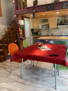a kitchen with a red table and some chairs at le loft de l'Atelier in Nans-sous-Sainte-Anne
