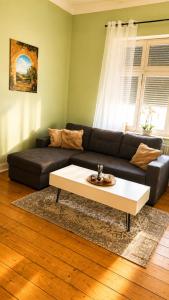a living room with a black couch and a coffee table at Pension zum Ziegenbart in Tangermünde
