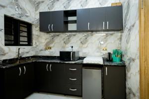 a kitchen with black cabinets and a marble wall at Famous Apartments in Ologode +7 photos