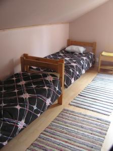 a bedroom with two beds and a rug at Majatalo Tyrni in Nakkila +8 photos