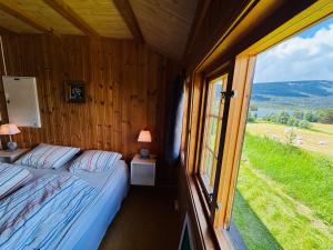a bedroom with a bed and a large window at Atmospheric cabin by Lesjaskogsvatnet in Lesja