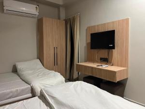 a bedroom with two beds and a desk with a television at hotel a sons in Chittaurgarh