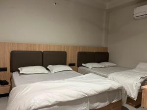 two beds in a room with white sheets at hotel a sons in Chittaurgarh +6 photos