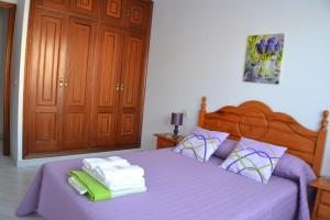 a bedroom with a purple bed with towels on it at Céntrico Apartamento Rosalía 3H in O Grove