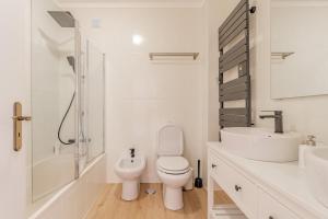 a white bathroom with a toilet and a sink at Baleal Happiness Surf House in Baleal