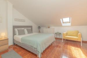a bedroom with a bed and a yellow chair at Baleal Happiness Surf House in Baleal