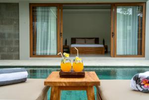 two drinks on a table next to a pool at Villa Lombok Surga Kedua Setangi in Mangsit