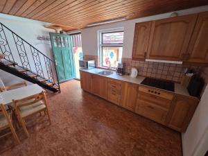 a large kitchen with wooden cabinets and a staircase at Holiday Apartment Rudkøbing in Rudkøbing +8 photos