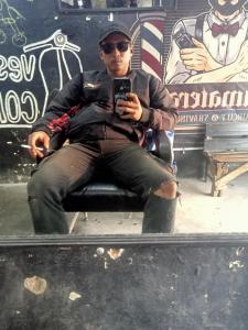 a man sitting in a chair taking a picture in a mirror at Hotel in Panenjoan