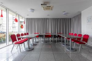 een vergaderzaal met rode stoelen en tafels en ramen bij Algiro Hotel in Kaunas