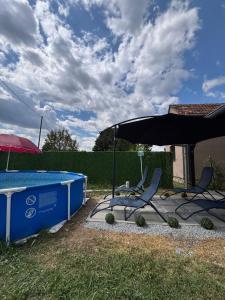 two chairs and an umbrella next to a swimming pool at Kuća za odmor Štiba in Vinkovci