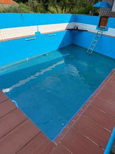 a blue swimming pool with a ladder in it at O cantinho da Esther in Bustos