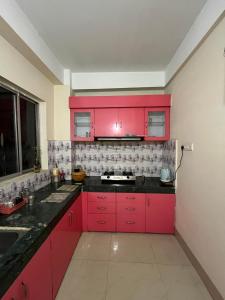 a kitchen with red cabinets and black counter tops at Pure Bliss 3BHK Stay in Guwahati